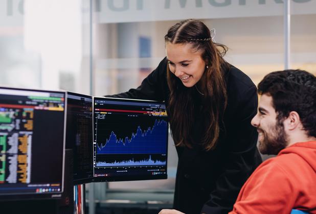 Students in a financial lab environment in a university setting looking at graphs on two screens