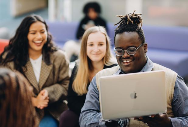 Three students looking at a laptop