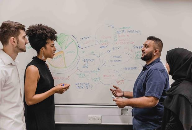 Business management students adding ideas onto a whiteboard