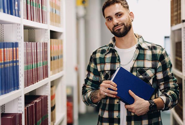 Male law student in the Sheppard Library standing between book shelves