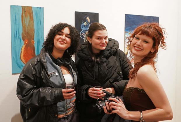 Three students smiling at the camera at an art show