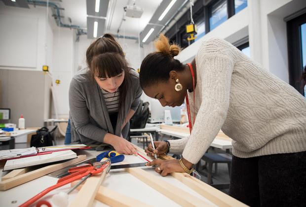Students measure and mark wooden materials during an interior design workshop.