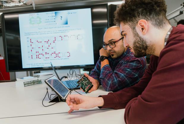 Students and a lecturer work with electronic hardware and software during an engineering class