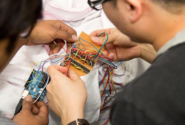 Two male students sitting at a desk, working on a piece of electronic equipment