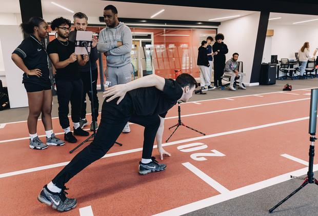Sport and exercise students analyse an athlete's movement using digital equipment in a performance laboratory.