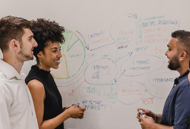 Business students work together on a group activity using a whiteboard.