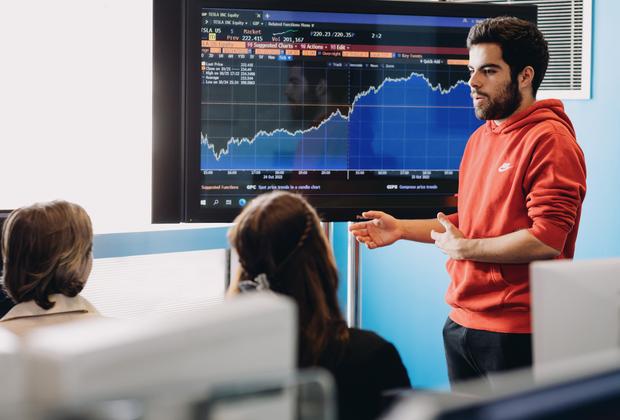 Students analyse financial charts and data visualisations during a computing seminar.