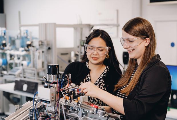Two students working on a robot arm