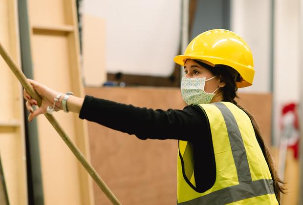 Student with hardhat, facemask and hi-viz vest holding long stick