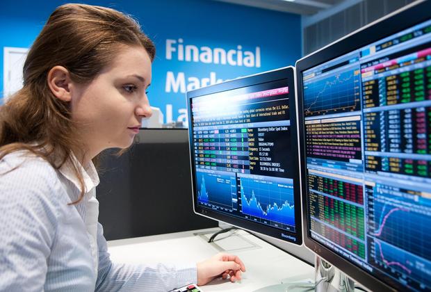 A female student sitting in front of a computer monitor displaying financial data in the Financial Markets Lab
