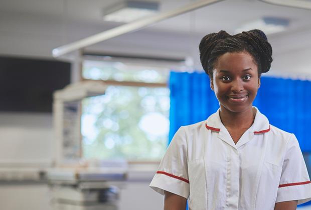 Two nurses assisting a baby in a hospital room.