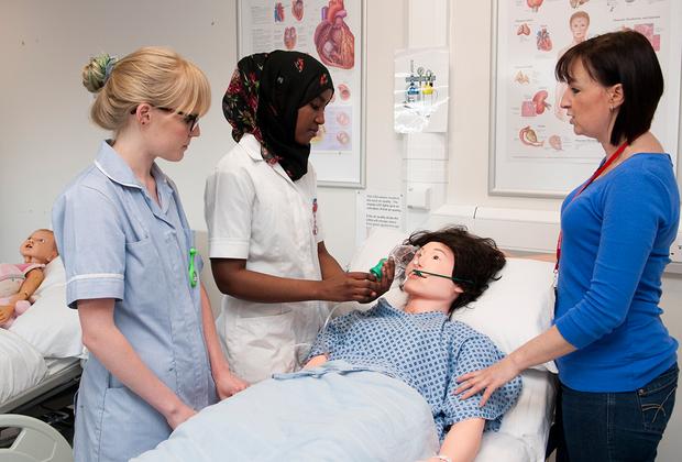 student nurses examining a dummy in class