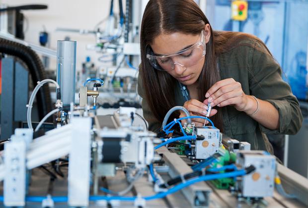 female student wearing googles works on circuitry with small screwdriver