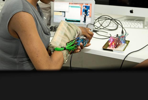 A student is sitting at a desk in front of a computer, working with electrical equipment