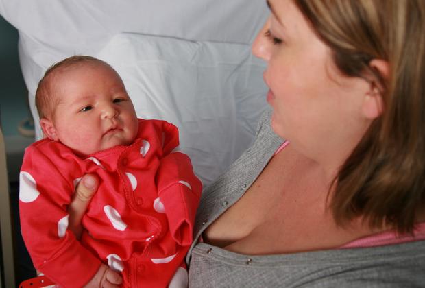 Mother holding baby in red spotted baby grow