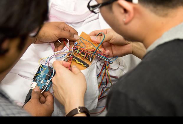 Two male students sitting at a desk, working on a piece of electronic equipment