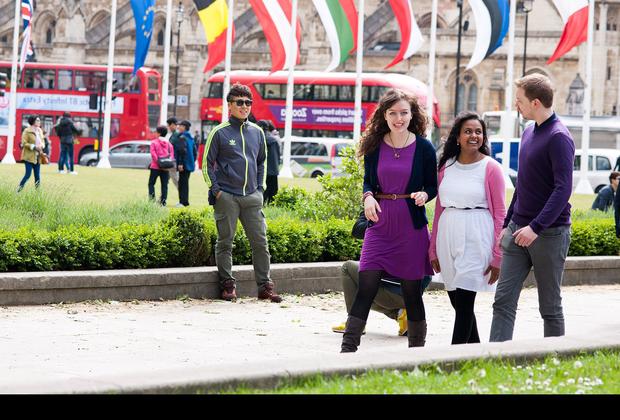 Three young people walking in a park, enjoying nature and each other's company. A perfect representation of international tourism and hospitality.