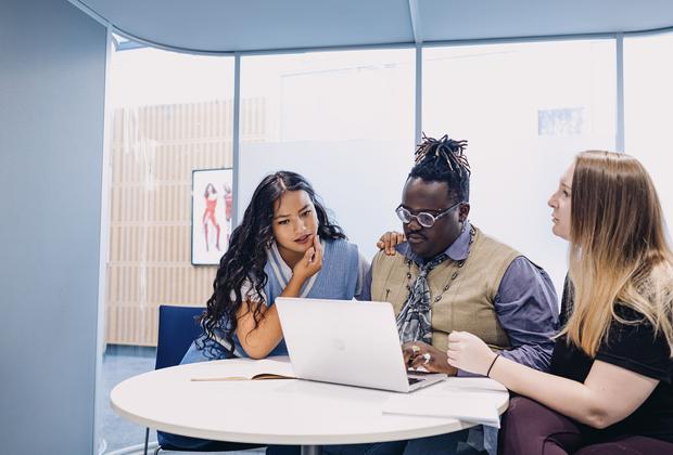 three students work together on laptop
