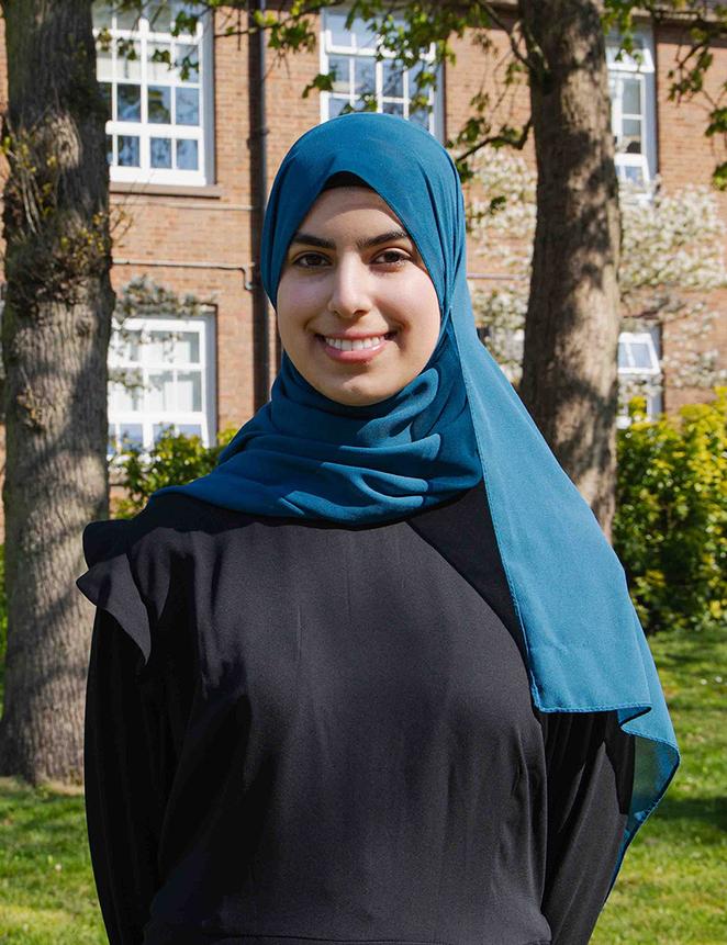 Duha stood on campus on a sunny day with campus building in background