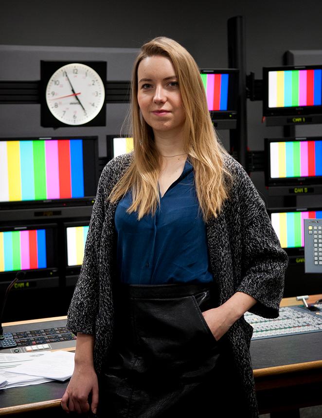 student stands in television studio control desk