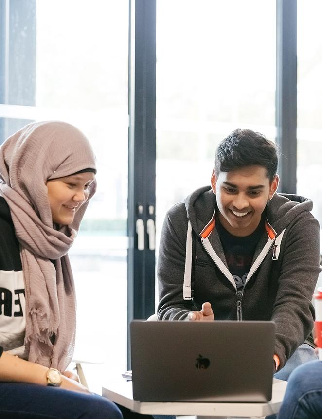 Two students work informally together at laptop