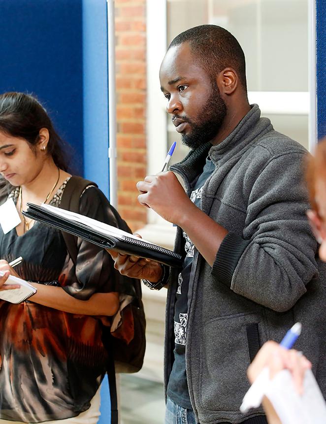 research students at conference taking notes on clipboards
