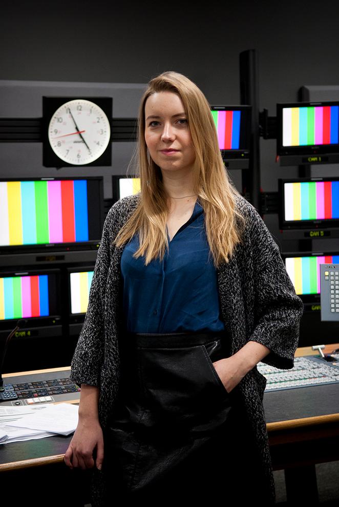 student stands in television studio control desk