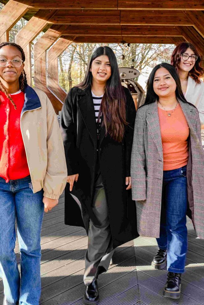 Six students walking together under a wooden structure