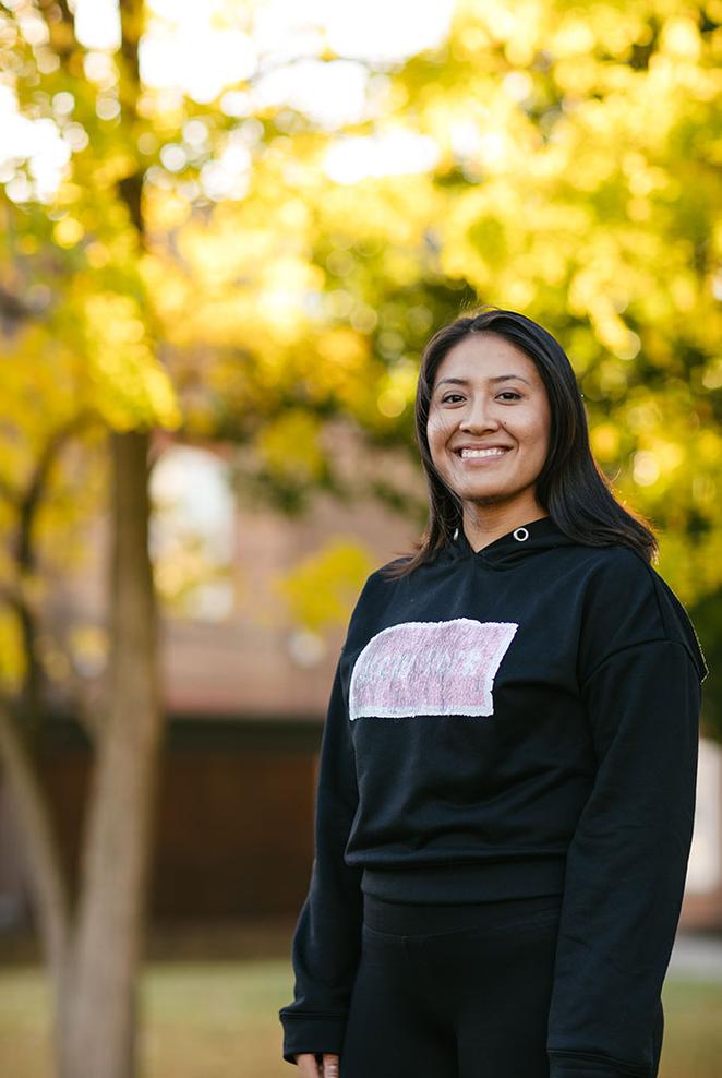Student smiling in front of autumnal tree