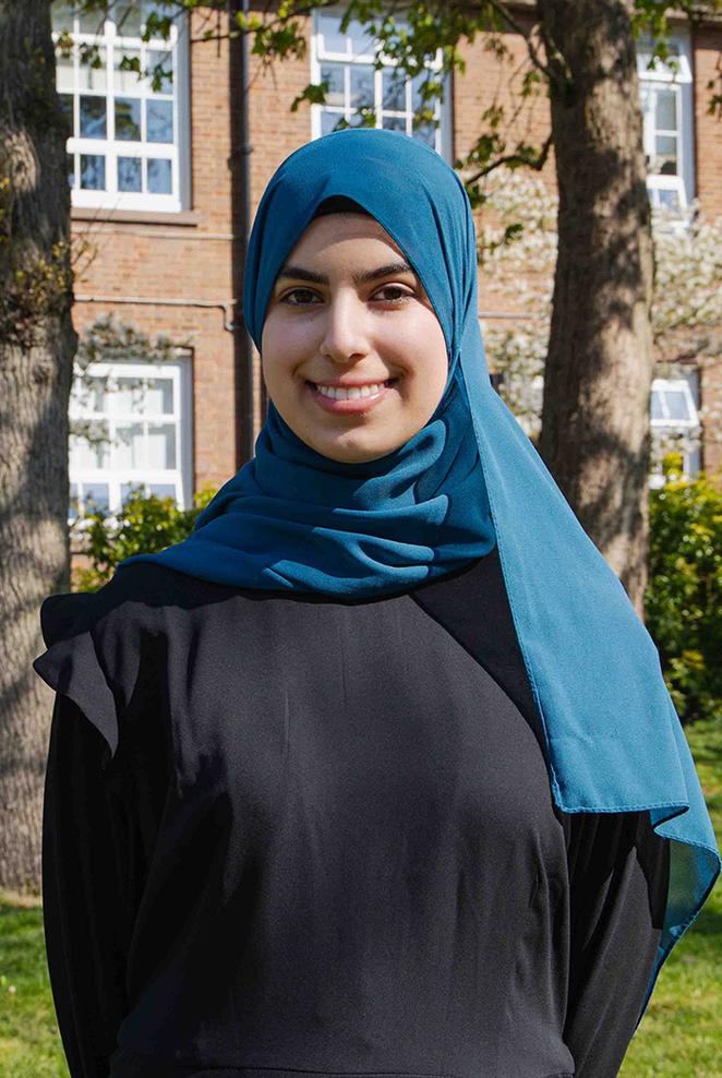 Duha stood on campus on a sunny day with campus building in background