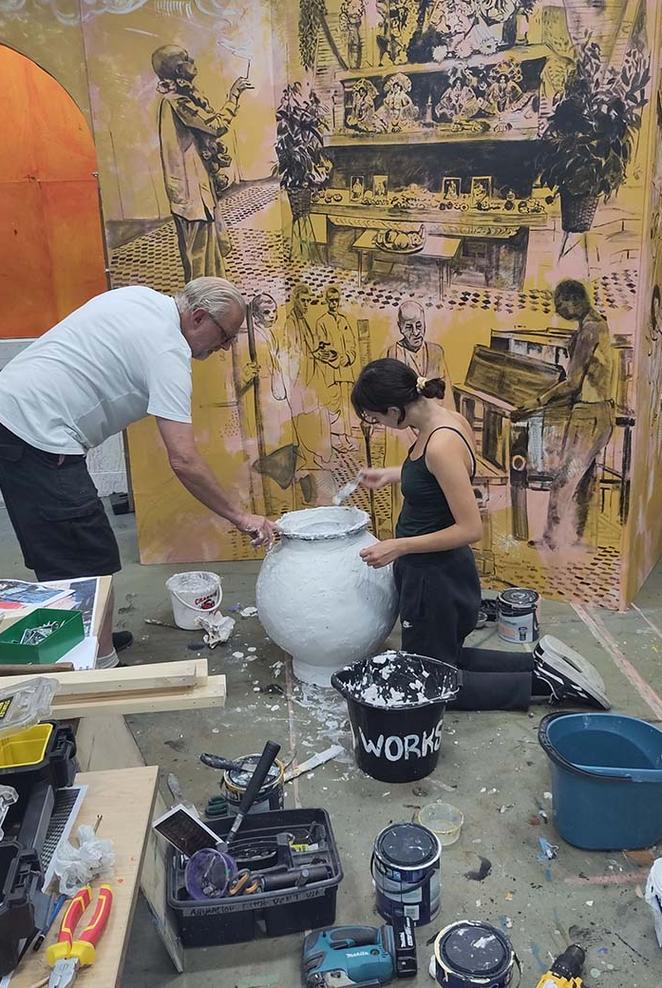 Student working painting a pot for a film set