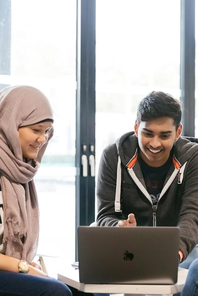 Two students work informally together at laptop