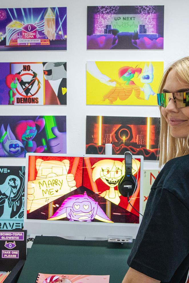 Girl wearing glasses stood in front of gallery of animation work