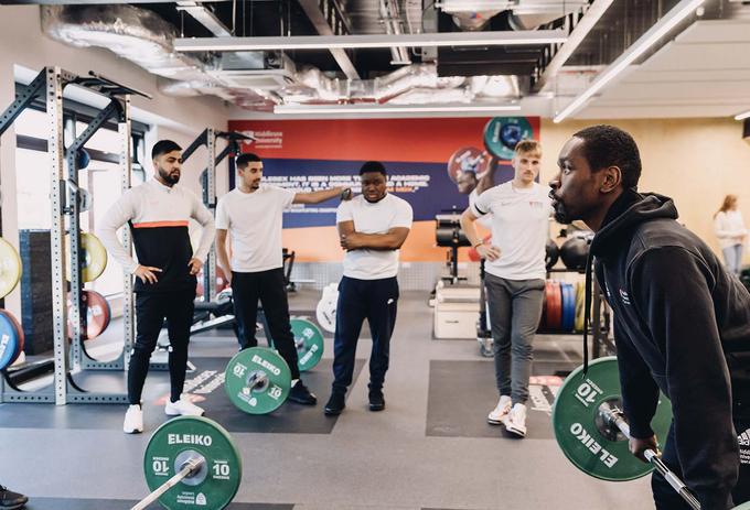 Students taking part in gym strength exercise.
