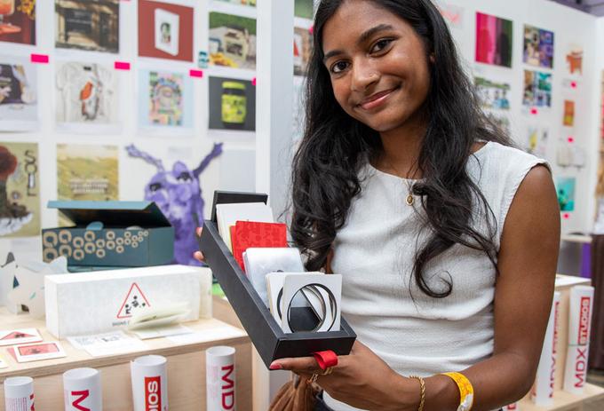 A female student holding up their work at a creative festival