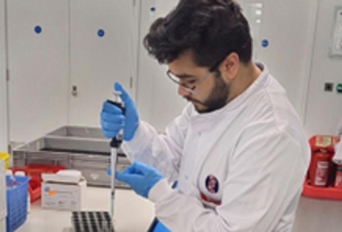 Young student wearing a white coat filling in laboratory test tubes
