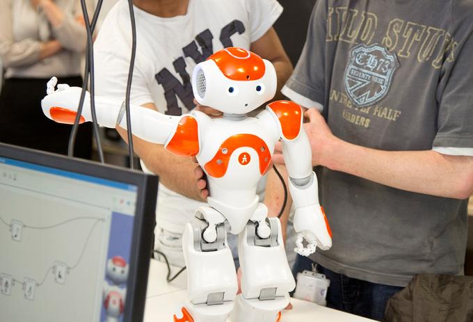 student holds small white robot