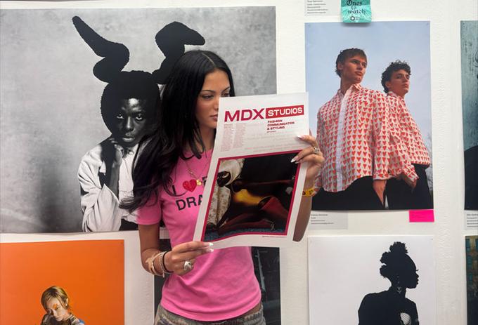 Creative student standing with work at exhibition