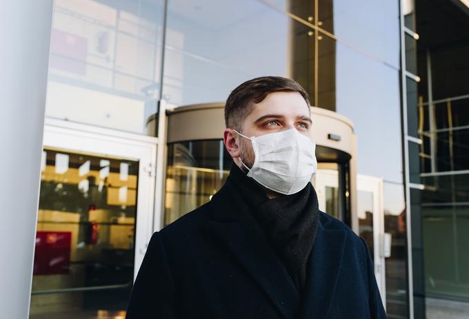 An individual wearing a face mask with a building in the background.