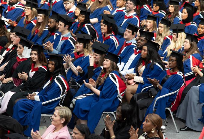 A crowd of graduating students sitting in their graduation robes and mortar boards