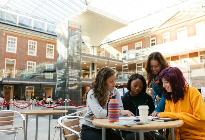 students sitting at a desk chatting with refreshments
