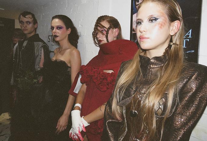 Three models stand together wearing pieces from a collection
