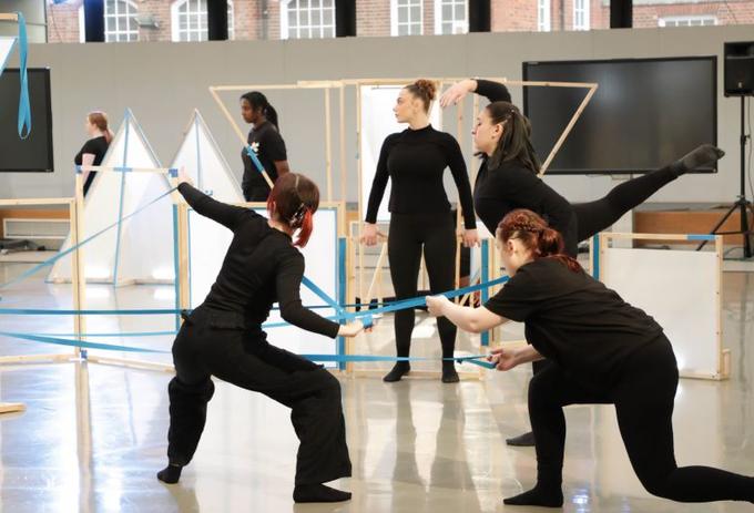 Group of dance students practise routine with stage props.