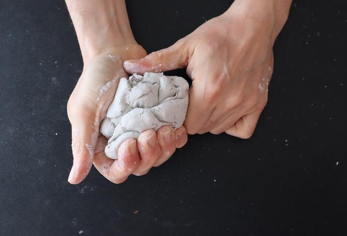 A pair of hands moulding clay on a black background