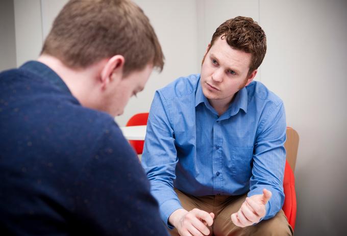 A person sitting on a couch talking to a therapist. They are engaged in a conversation about mental health and social work.