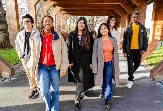 Six students walking together under a wooden structure