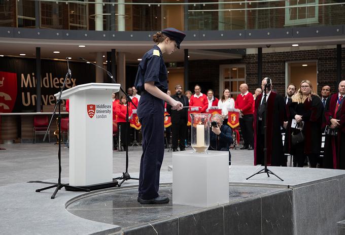 A cadet lights a candle at a memorial event