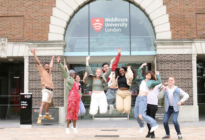 Group of students jumping with joy in front of Middlesex University building