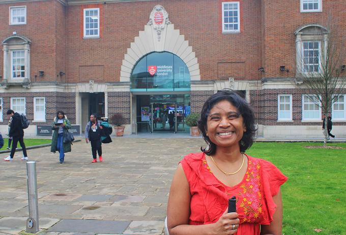 Woman in red top stands outside university