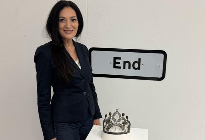 Woman stands next to crown at exhibition